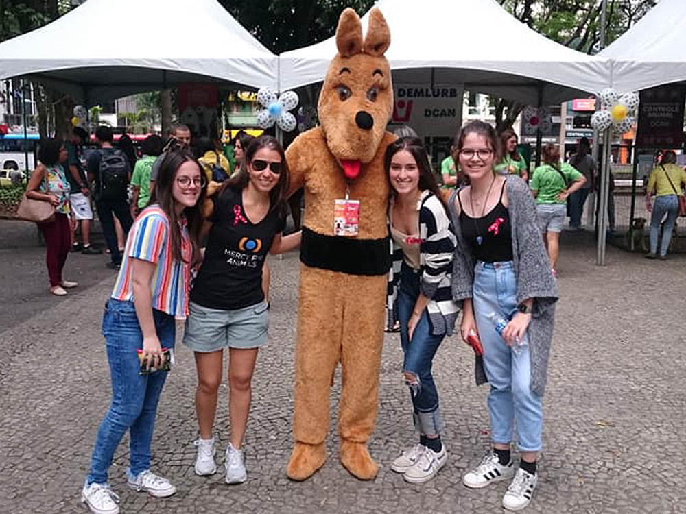 MFA volunteers posing with a person dressed up like a dog at an outreach event